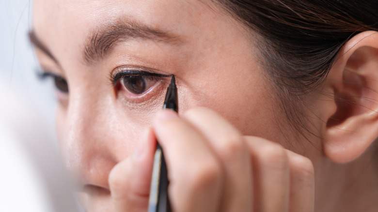Une femme appliquant un eye-liner ailé avec un stylo