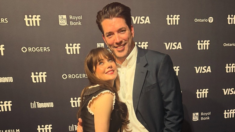 Jonathan Scott embrasse Zooey Deschanel sur le tapis rouge du TIFF alors qu'elle lève les yeux d'un air ludique dans une robe noire