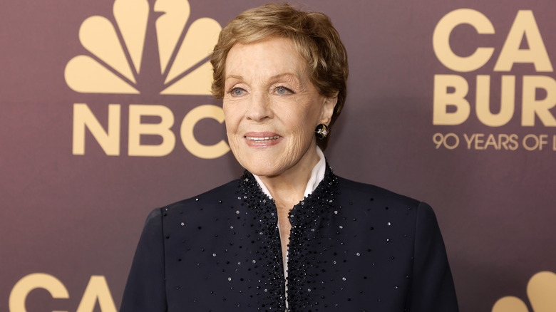 Julie Andrews souriant lors d'un événement NBC 2023 tout en portant une veste bleue décorée de paillettes
