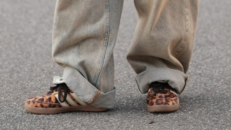 Les pieds d'une femme portant des baskets à imprimé léopard avec un jean retroussé