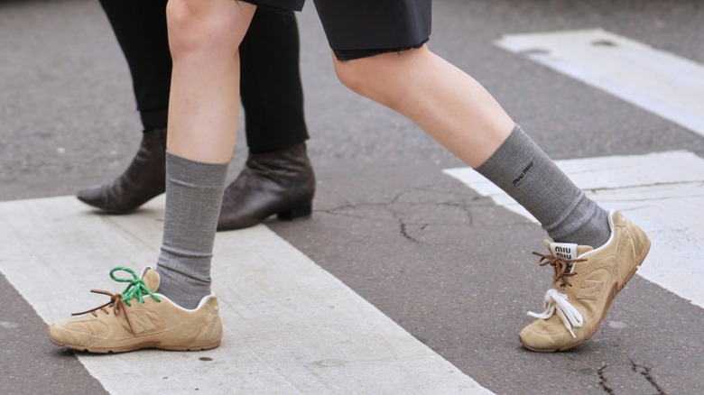 Les pieds d'une femme traversant la rue en portant des baskets en daim beige