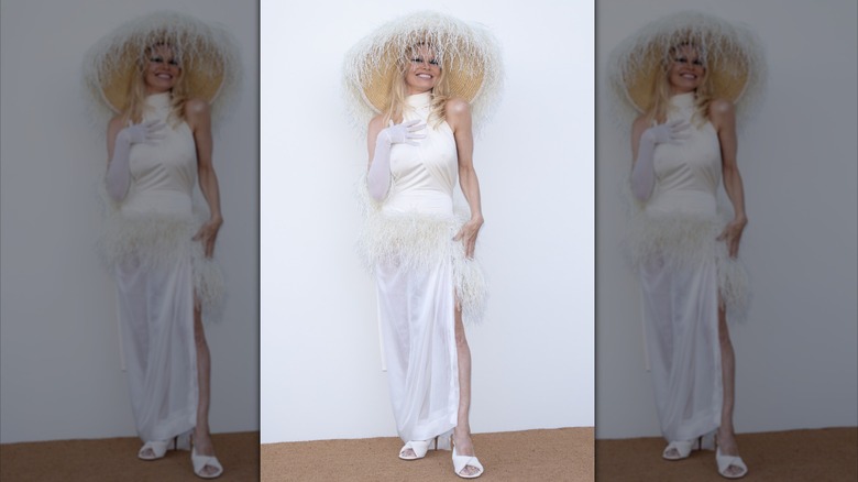 Pamela Anderson dans un grand chapeau et une robe blanche avec des talons blancs