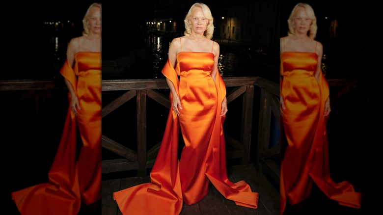 Pamela Anderson dans une robe orange avec un long châle orange lors d'un événement