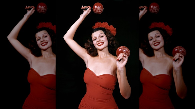 Rita Hayworth posant avec des maracas dans une tenue rouge monochrome