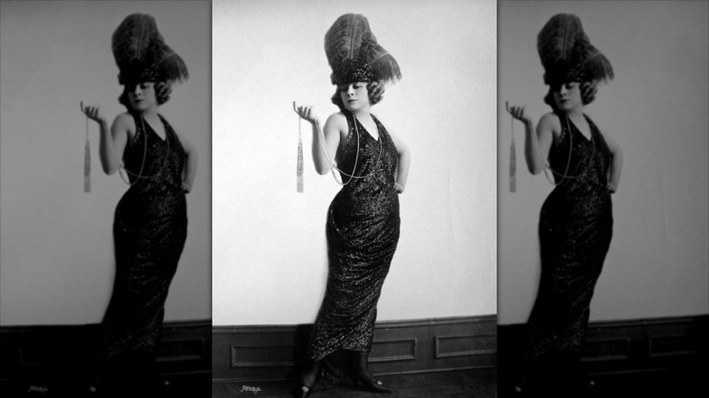 Photo en noir et blanc de Mae West portant une robe à sequins et une coiffe en plumes