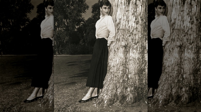 Audrey Hepburn portant une jupe noire et une chemise blanche avec des escarpins noirs