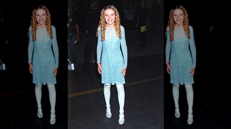 Kirsten Dunst sourit en portant une robe bleue à paillettes et des chaussures plates en gelée.