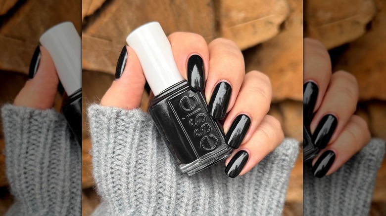 Gros plan sur les ongles d'une personne peints avec de la réglisse Essie et tenant la bouteille de vernis à ongles