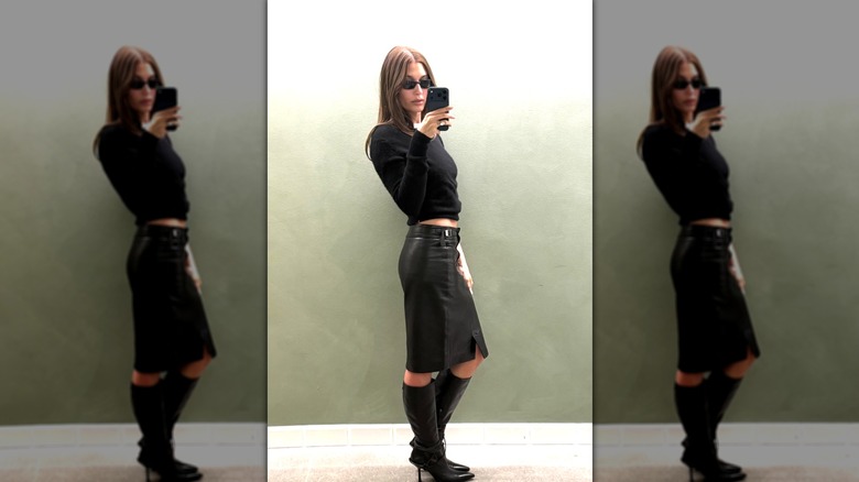Hailey Bieber portant une jupe en cuir noire et des bottes noires avec un pull en tricot noir