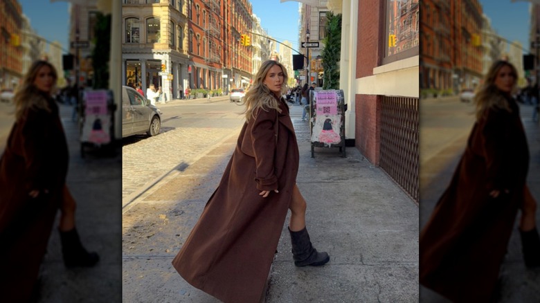Sophia Tuxford portant un long manteau marron avec des bottes marron souples