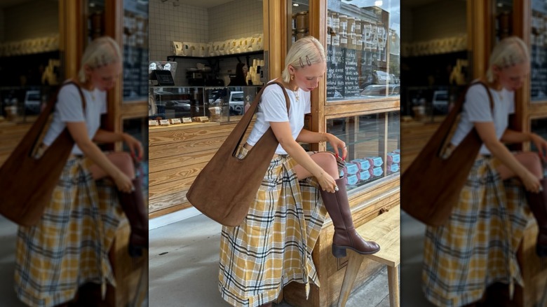 Chloé Davie portant des bottes marron, un haut blanc et une jupe à carreaux jaune et marron