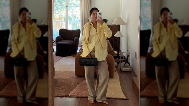 Aimee Song porte une chemise jaune beurre avec un pantalon large beige.