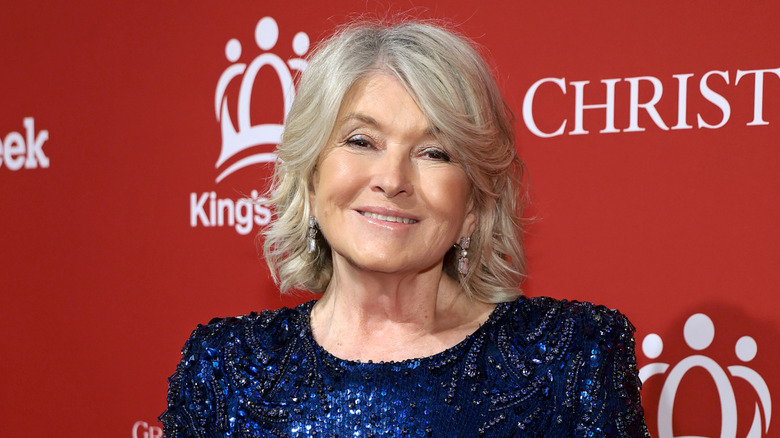 Martha Stewart dans une robe bleue à paillettes devant un fond rouge