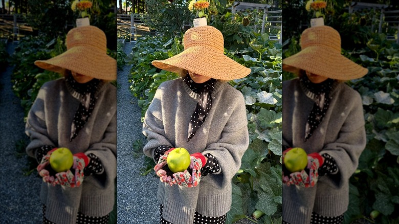 Pamela Anderson tenant une pomme dans son jardin