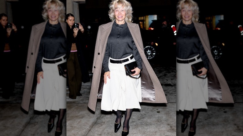 Pamela Anderson portant une chemise noire sur une jupe blanche