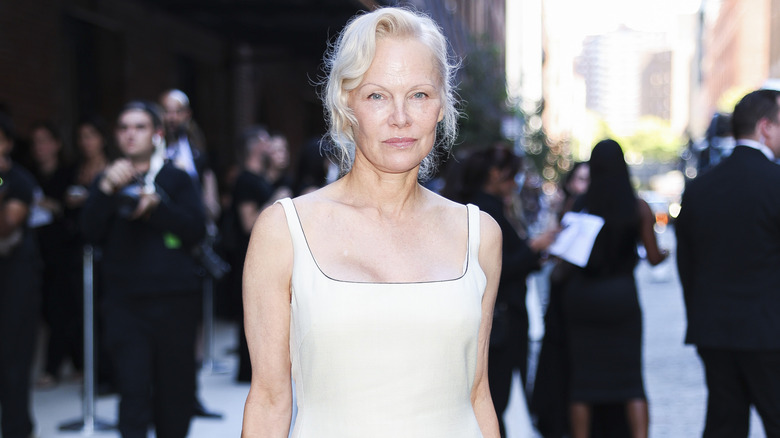Pamela Anderson posant en extérieur dans une tenue blanche et lumineuse, sans maquillage