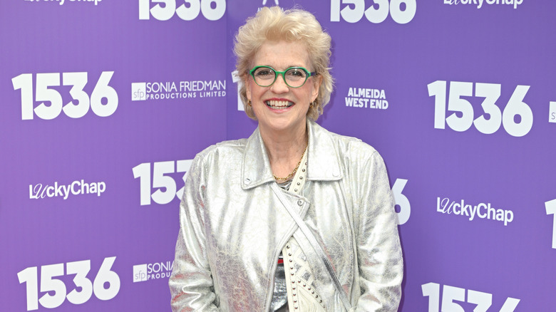 Hilary Gish Whitehall souriant tout en portant une veste argentée et des lunettes vertes lors d'une soirée d'ouverture du West End en 2026
