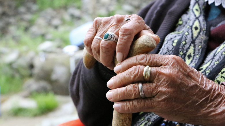 Les mains d'une femme à l'extérieur portant des anneaux tenant une canne