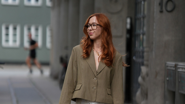 Une femme rousse portant un blazer vert kaki