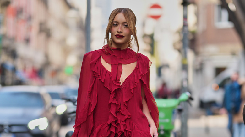 Une femme rousse portant une robe rouge à volants