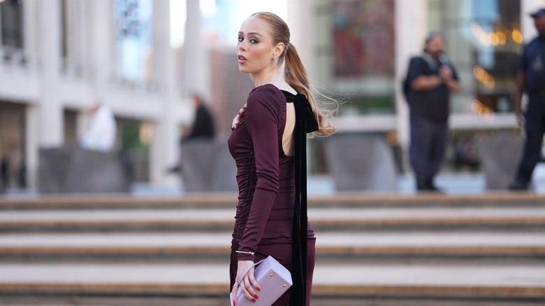 Une femme rousse portant une robe prune