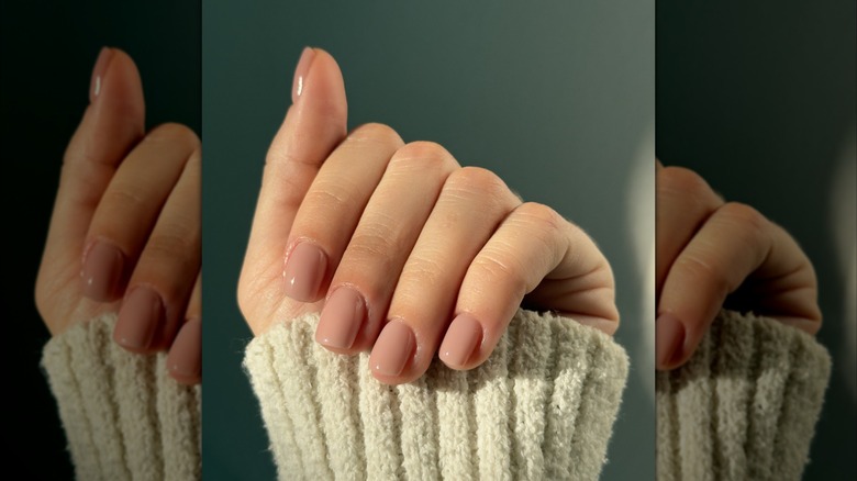 Une femme montre ses ongles roses nude