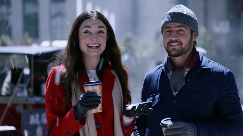 Tyler Hynes dans un manteau et un chapeau avec une femme en manteau rouge dessus 