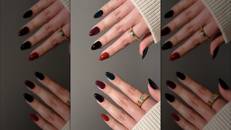 Mains avec une manucure Skittles avec chaque ongle peint d'une couleur foncée différente
