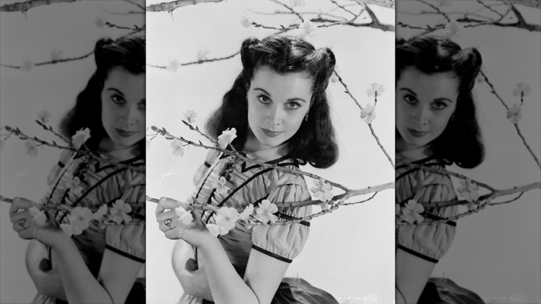Vivien Leigh sourit derrière un arbre en fleurs avec des rouleaux de victoire.