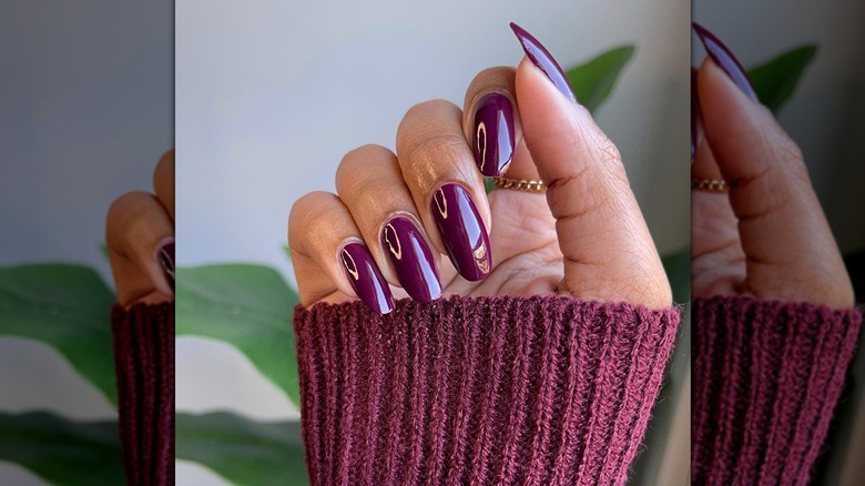 Main vaguement fermée montrant un vernis à ongles prune foncé avec une finition brillante