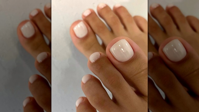 Une femme avec une pédicure blanche et claire