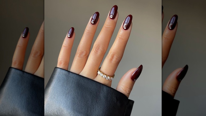 Une femme montre sa manucure bordeaux.