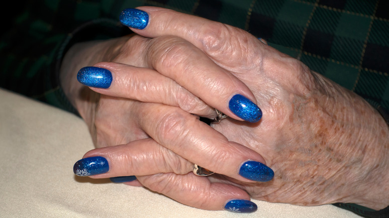 Une femme plus âgée se vernit les ongles.
