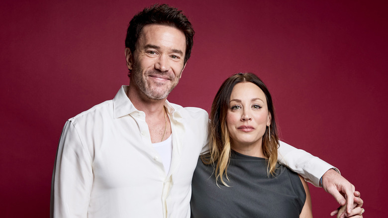 Kaley Cuoco et Tom Pelphrey lors d'un événement devant un écran rouge