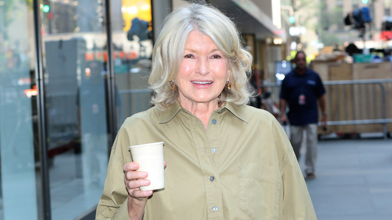 Martha Stewart posant avec un verre de vin assise sur un banc en bois